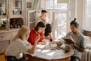 Image of a group of four people engrossed in their studies, sitting around a kitchen table filled with books and papers. In this scenario, the image symbolizes the Glossary of Lead Generation terms from Lead Launcher.