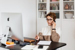 Sales development executive in an office setting, engaging in a crucial conversation over her mobile phone, demonstrating the importance of communication in driving sales.