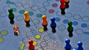 A silver board game with blue, orange, red, and yellow pieces symbolizing various buyer personas in a business strategy context.