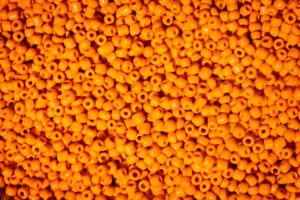 This image showcases a close-up, fill-the-frame photograph of numerous vibrant orange beads densely packed together. The beads, all identical and impersonal, represent the lack of personalization inherent in the Spray and Pray method. Each bead's sameness to the next mirrors the uniform approach of this strategy, where efforts are broadly spread with little regard for individual nuances. The intense dominance of the orange color signifies the overwhelming saturation often associated with the "Spray and Pray" technique. This image serves as a visual metaphor for the indiscriminate, non-targeted efforts often used in the "Spray and Pray" approach.